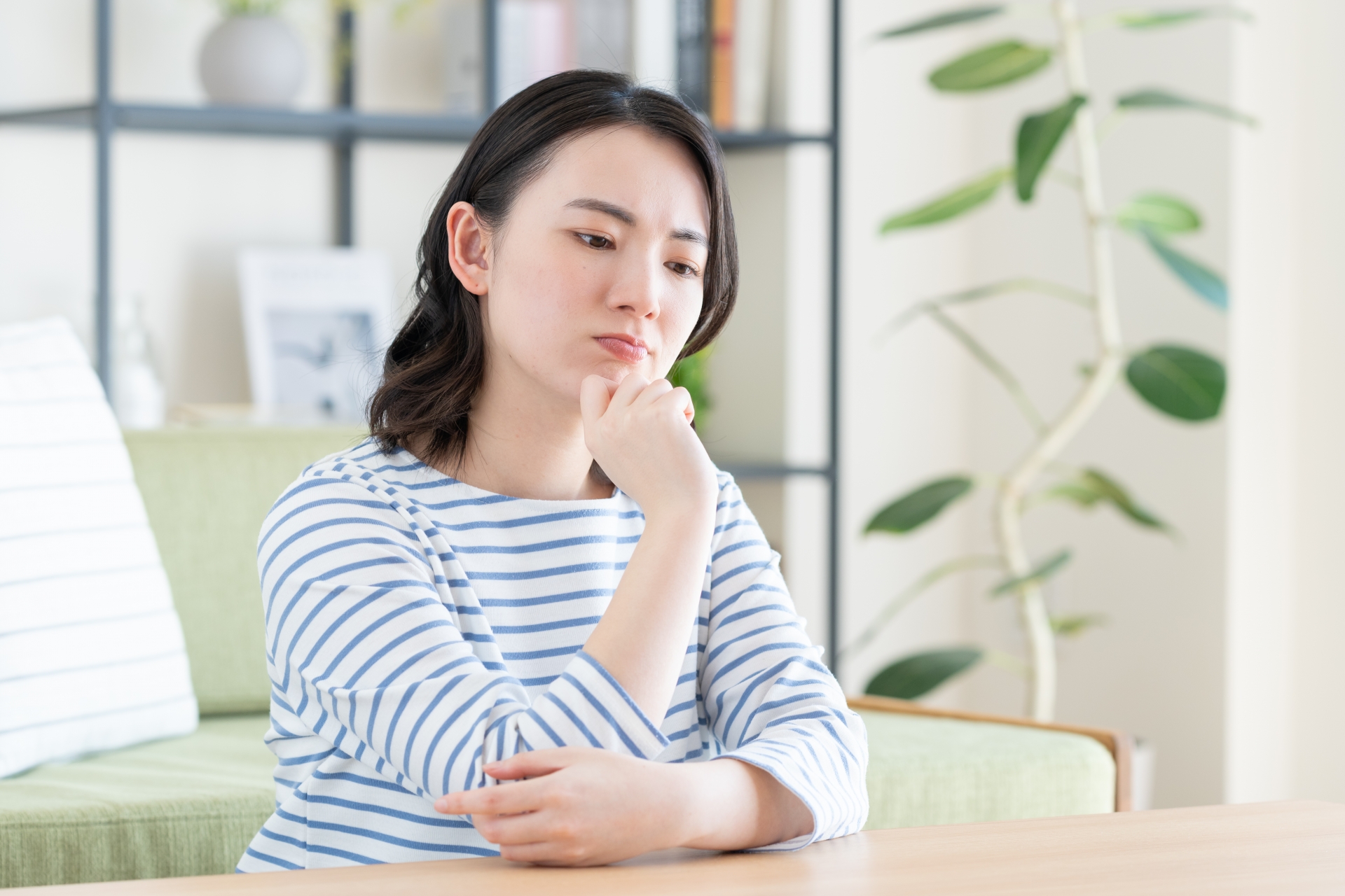 女性が肘をついて悩んでいる